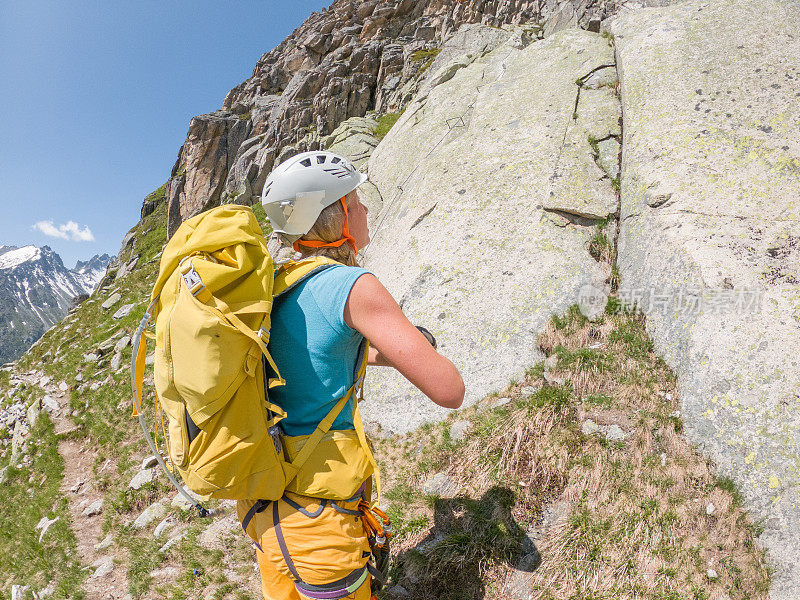 一位年轻女子准备在瑞士阿尔卑斯山开一辆Via Ferrata，她抬起头来